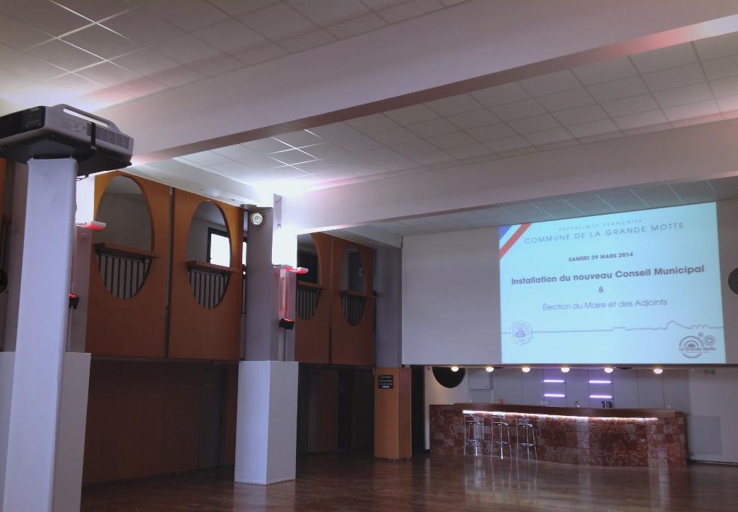 Salle des fêtes équipée d’un écran de projection pour un conseil municipal